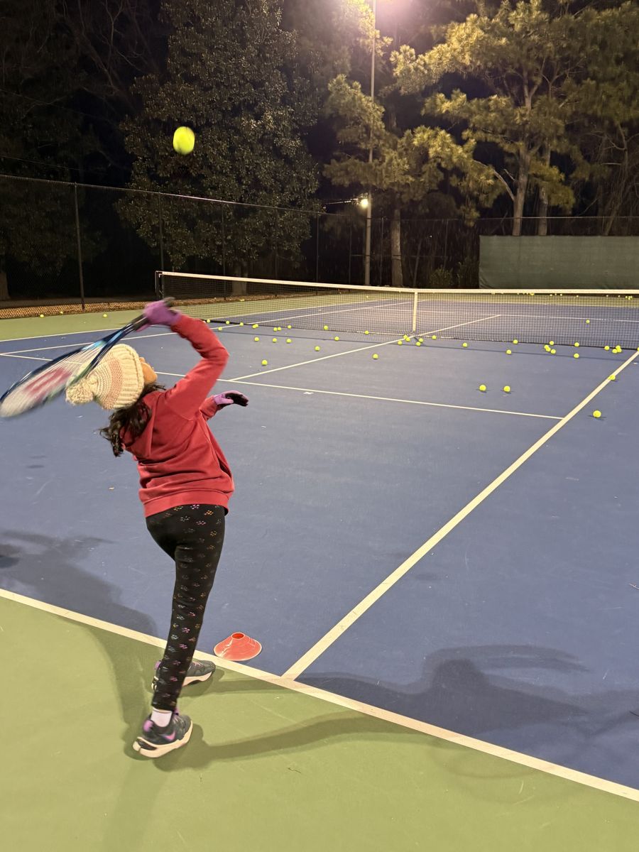 Big NC junior serving under the lights at an evening clinic