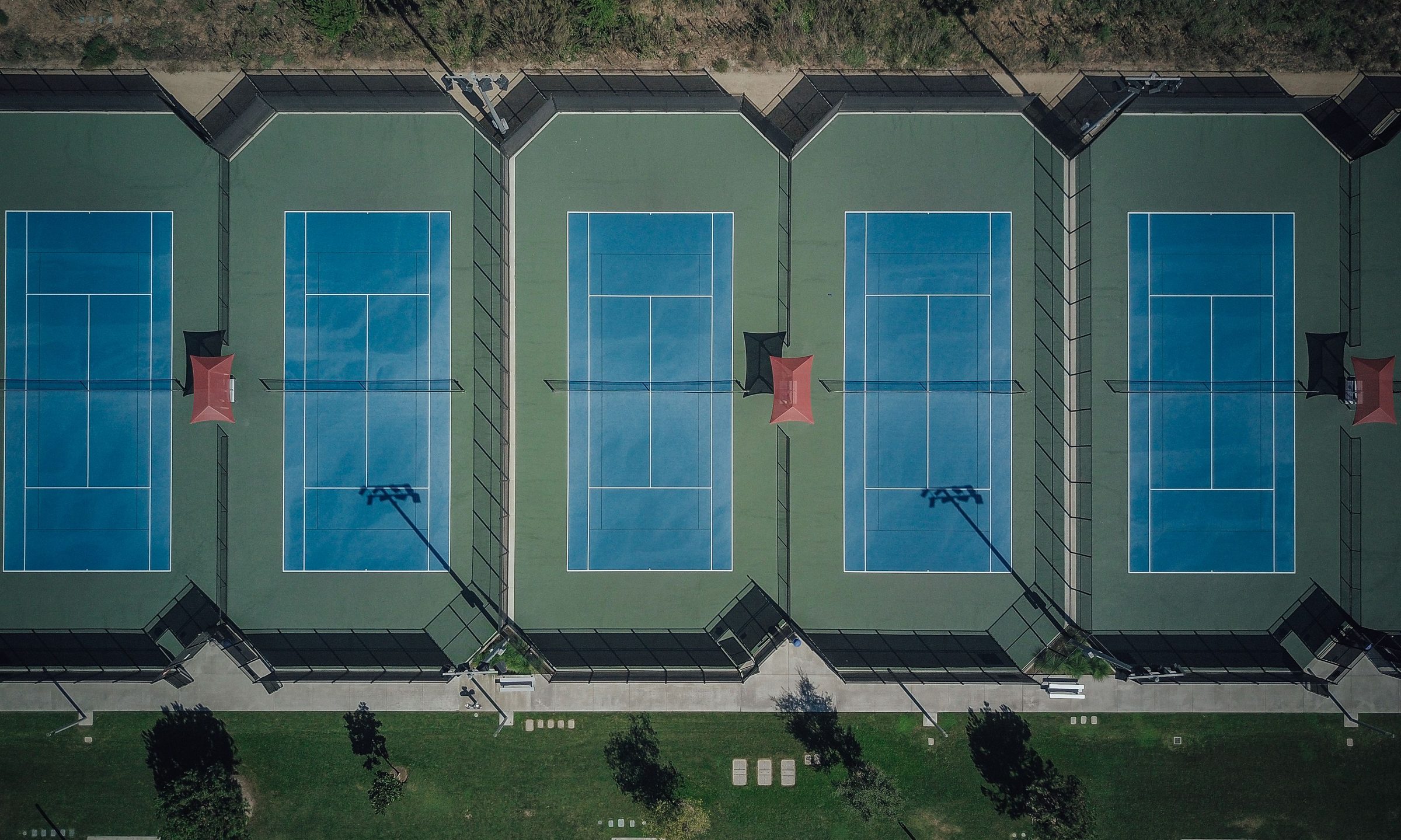 Aerial view of empty blue hard tennis courts with nets