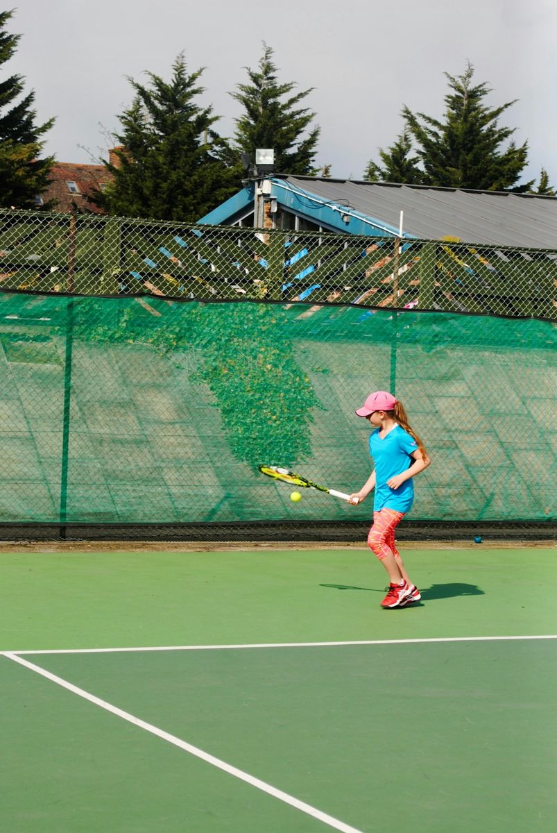 Junior player hitting on a green court
