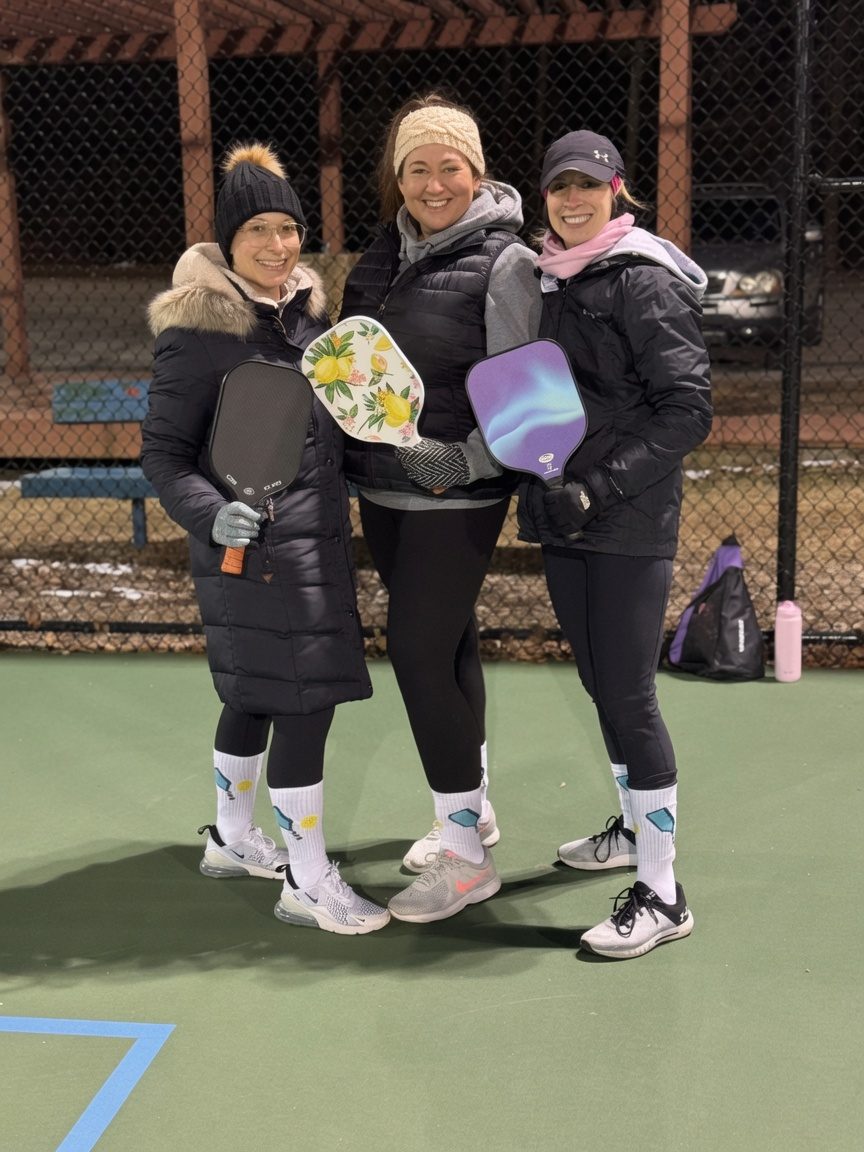 Three pickleball players with paddles on the Harnett courts